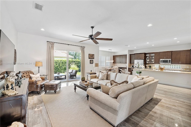 living room featuring ceiling fan and light hardwood / wood-style flooring