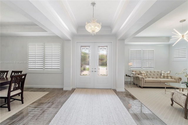 entrance foyer featuring a chandelier, hardwood / wood-style flooring, a raised ceiling, and crown molding