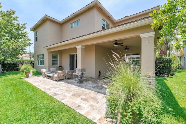 back of property with a lawn, ceiling fan, an outdoor living space, and a patio