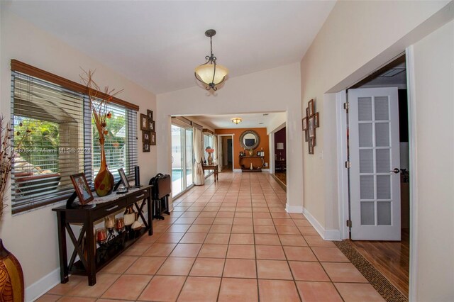 corridor with lofted ceiling and light tile patterned flooring