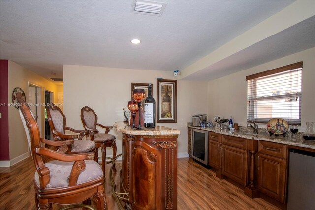 kitchen featuring light stone countertops, dark hardwood / wood-style flooring, wine cooler, and sink