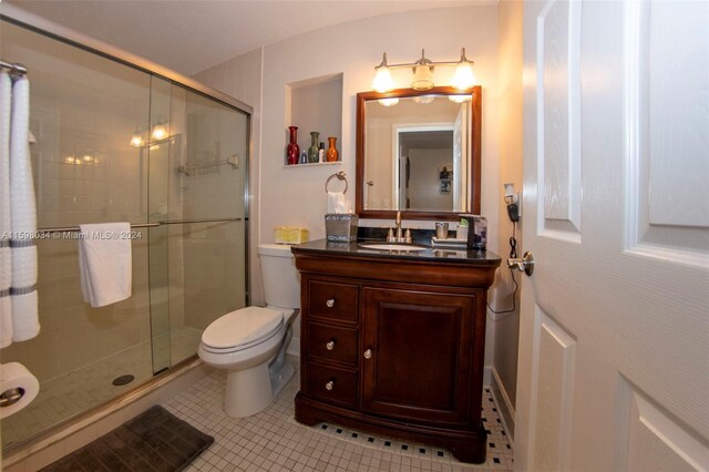 bathroom featuring tile patterned floors, vanity, toilet, and walk in shower