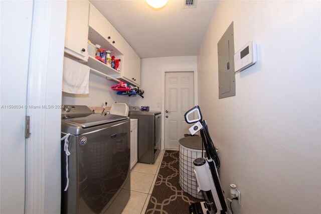 laundry room with washing machine and dryer, electric panel, light tile patterned floors, and cabinets