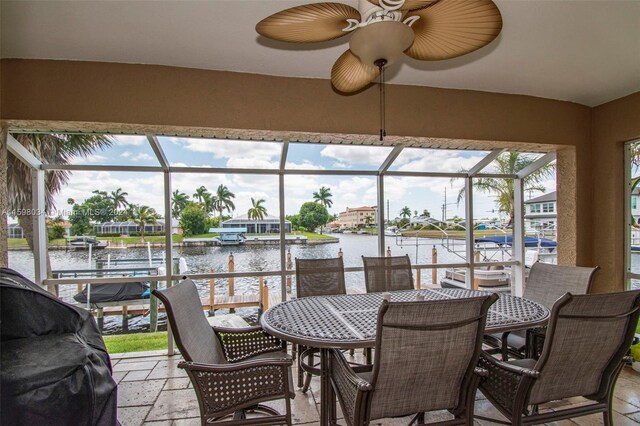 sunroom / solarium with ceiling fan and a water view