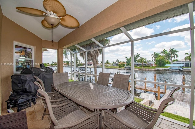 sunroom / solarium with ceiling fan, a water view, and vaulted ceiling