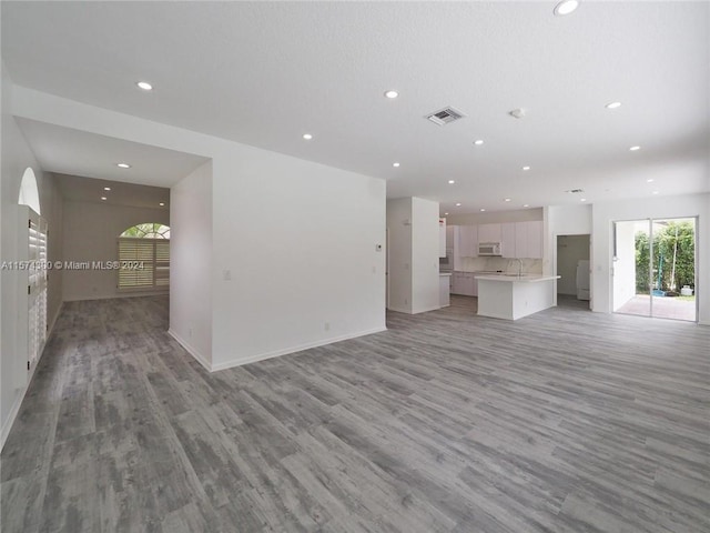 unfurnished living room featuring sink and light wood-type flooring