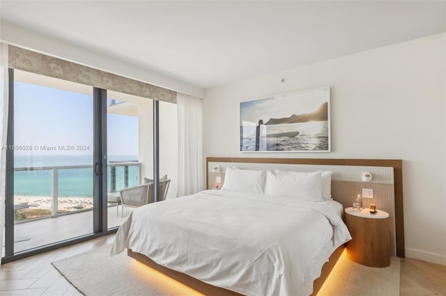 bedroom featuring access to outside, light wood-type flooring, and a water view