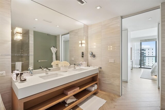 bathroom with vanity with extensive cabinet space, double sink, parquet flooring, and tile walls