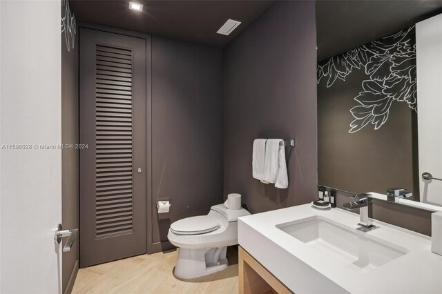 bathroom with hardwood / wood-style floors, toilet, and vanity