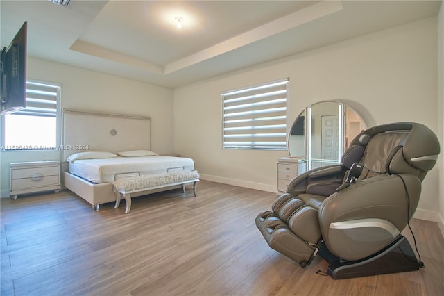 bedroom with a raised ceiling and light hardwood / wood-style floors