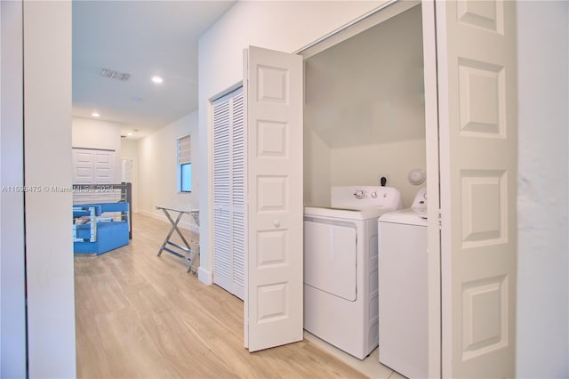 clothes washing area featuring washer and clothes dryer and light hardwood / wood-style floors