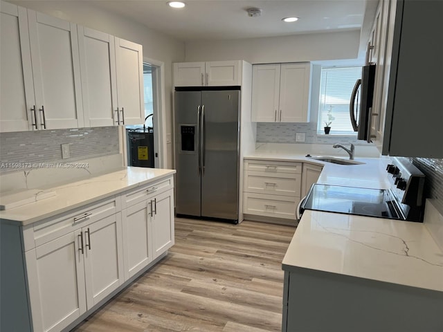 kitchen featuring white cabinets, stainless steel appliances, light stone counters, and sink