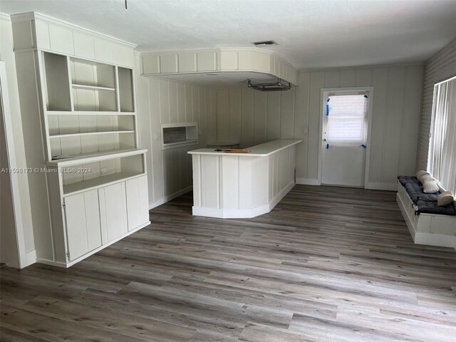 kitchen with built in shelves, ornamental molding, hardwood / wood-style flooring, and white cabinets