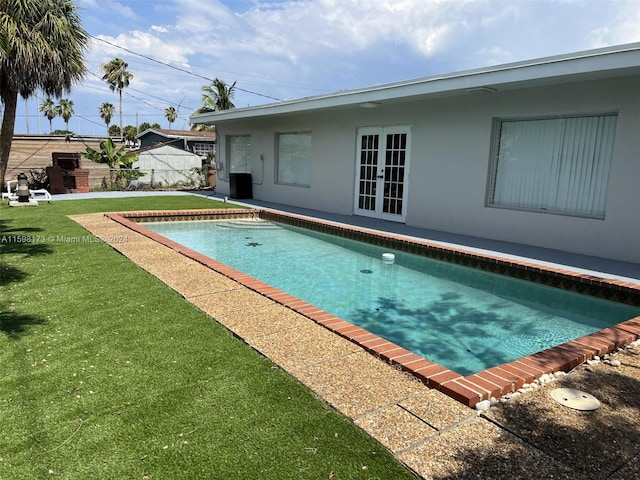 view of swimming pool with french doors and a lawn