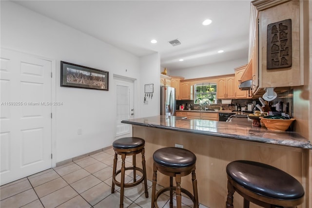 kitchen featuring kitchen peninsula, stainless steel refrigerator with ice dispenser, light tile floors, sink, and a kitchen bar