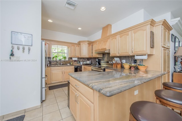 kitchen with stainless steel appliances, kitchen peninsula, backsplash, light tile floors, and light brown cabinets