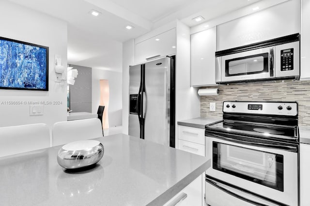 kitchen with decorative backsplash, stainless steel appliances, and white cabinetry