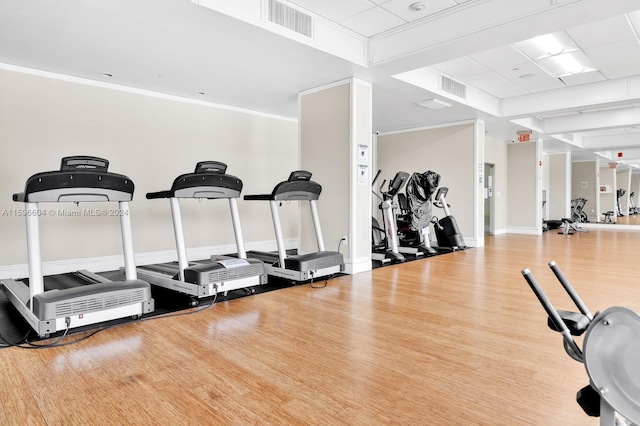 gym with light hardwood / wood-style floors and crown molding