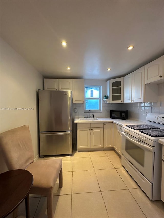 kitchen featuring stainless steel fridge, white gas range, and white cabinetry