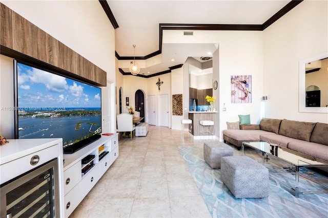 living room with crown molding, a water view, light tile flooring, a notable chandelier, and a towering ceiling