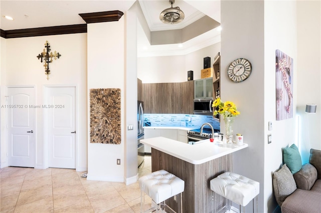 kitchen with crown molding, stainless steel appliances, kitchen peninsula, tasteful backsplash, and light tile floors