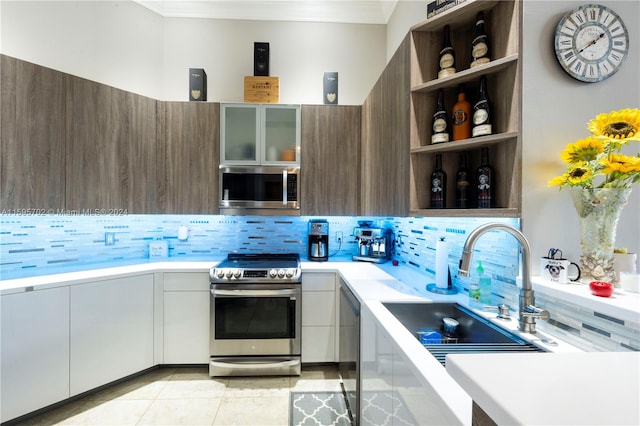 kitchen with ornamental molding, light tile floors, backsplash, and appliances with stainless steel finishes