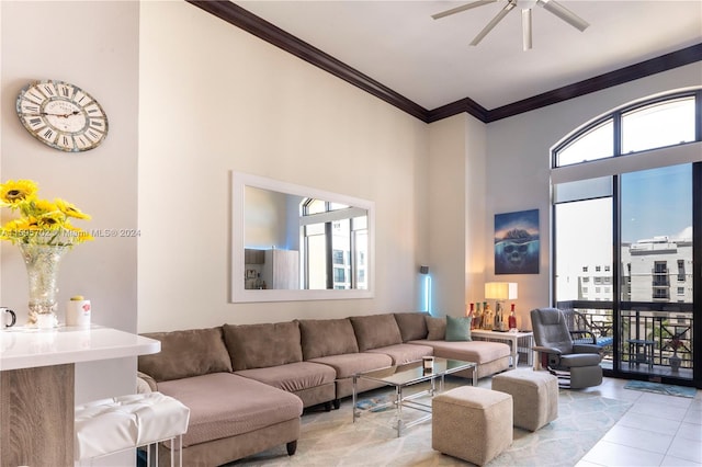 tiled living room with plenty of natural light, ceiling fan, crown molding, and a towering ceiling