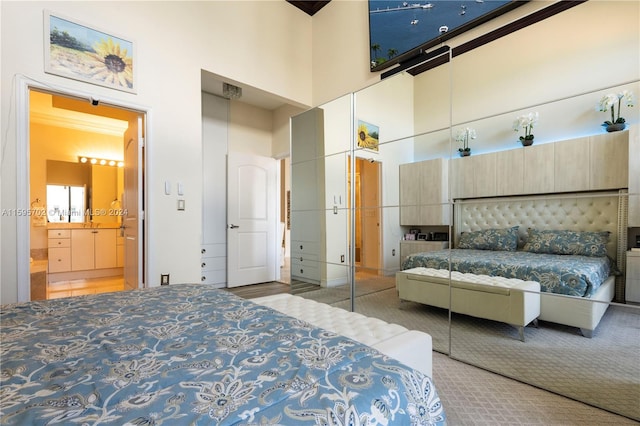 bedroom with a towering ceiling, carpet, and ensuite bath