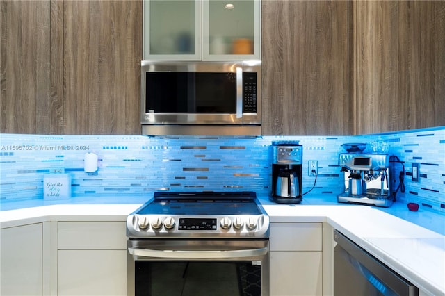 kitchen featuring stainless steel appliances, white cabinets, and tasteful backsplash