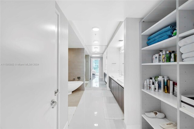 bathroom featuring a bath, tile floors, and large vanity