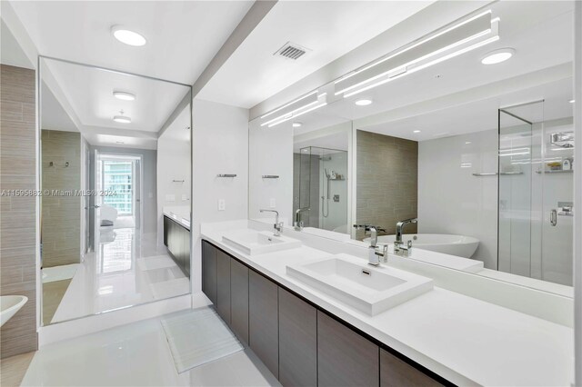 bathroom with tile floors, independent shower and bath, oversized vanity, and dual sinks