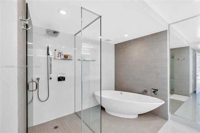 bathroom with tile flooring, shower with separate bathtub, and tile walls