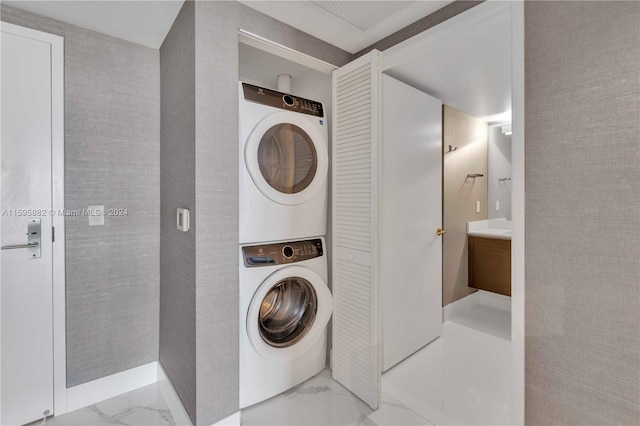 laundry area with stacked washer / dryer and light tile floors