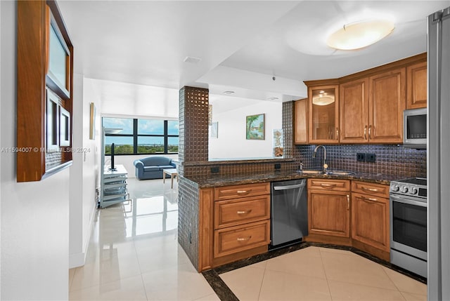 kitchen featuring sink, decorative backsplash, dark stone countertops, light tile patterned floors, and appliances with stainless steel finishes