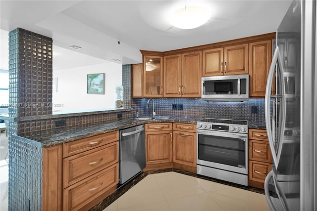 kitchen featuring sink, stainless steel appliances, backsplash, dark stone counters, and light tile patterned flooring