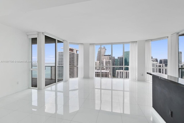 spare room with a view of city, light tile patterned flooring, and floor to ceiling windows