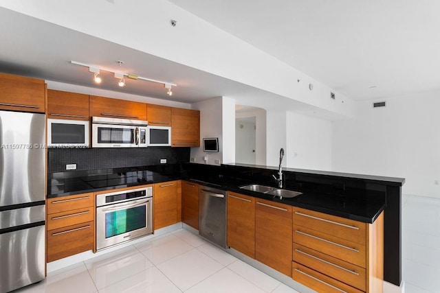 kitchen featuring stainless steel appliances, visible vents, brown cabinetry, a sink, and a peninsula