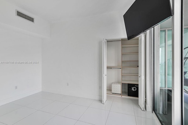 interior space featuring multiple windows, light tile patterned flooring, visible vents, and baseboards