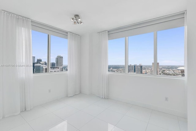 empty room featuring tile patterned flooring, baseboards, and a city view