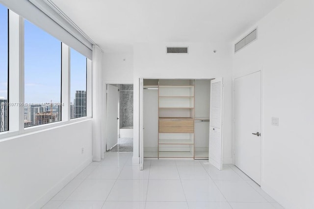 unfurnished bedroom with a closet, visible vents, baseboards, and light tile patterned floors