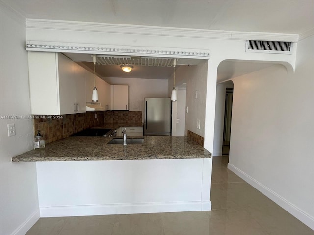 kitchen featuring decorative backsplash, stainless steel fridge, pendant lighting, and sink