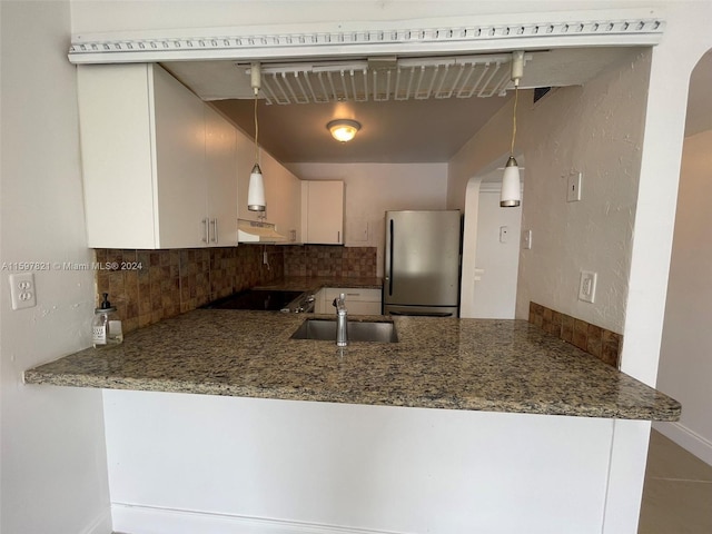 kitchen featuring stainless steel fridge, tasteful backsplash, tile patterned floors, cooktop, and sink