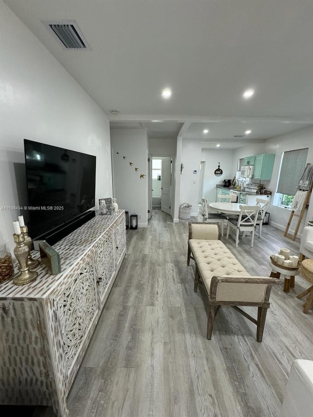 living area featuring baseboards, light wood finished floors, visible vents, and recessed lighting