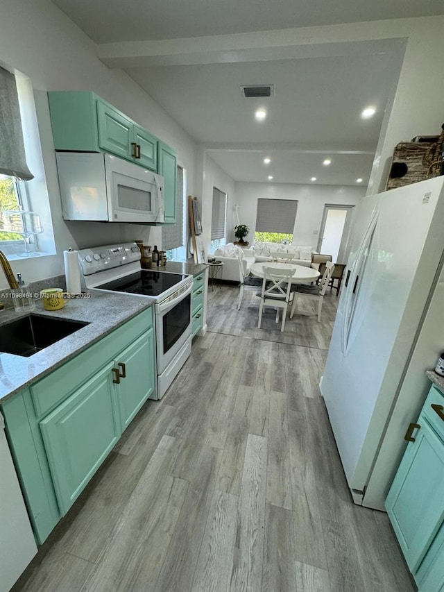 kitchen featuring light wood-style flooring, white appliances, a sink, visible vents, and green cabinets