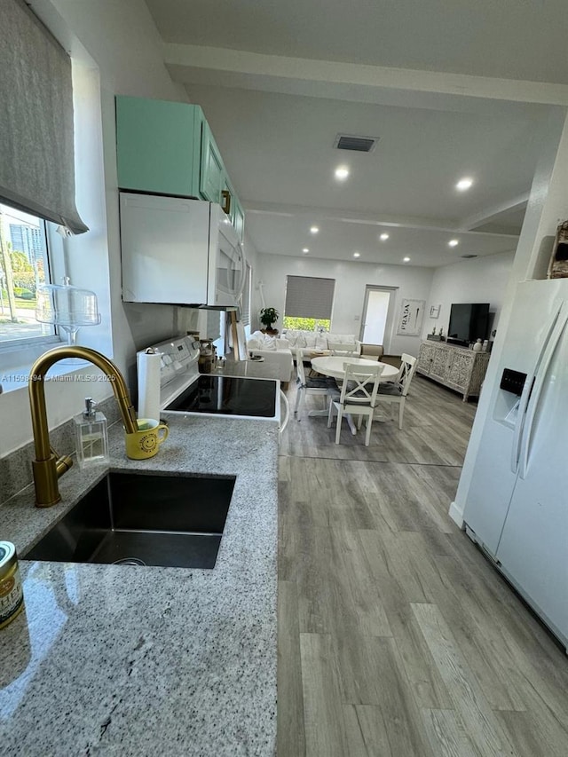 kitchen with visible vents, electric range oven, white microwave, a sink, and wood finished floors