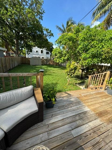 wooden deck featuring a fenced backyard, a storage unit, an outdoor structure, and a yard