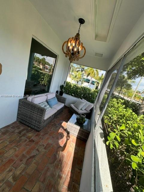 sunroom / solarium featuring a notable chandelier, plenty of natural light, and visible vents