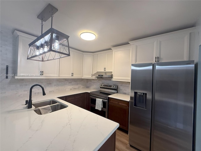 kitchen with appliances with stainless steel finishes, pendant lighting, white cabinetry, sink, and light stone counters