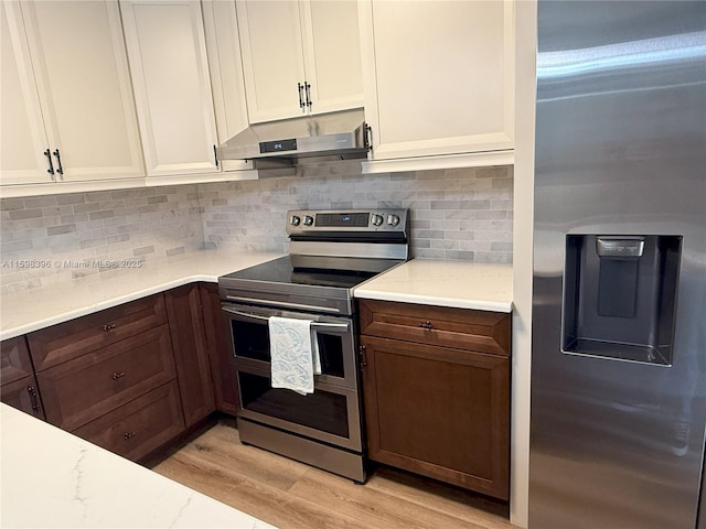 kitchen with white cabinetry, decorative backsplash, stainless steel appliances, light stone countertops, and light hardwood / wood-style flooring