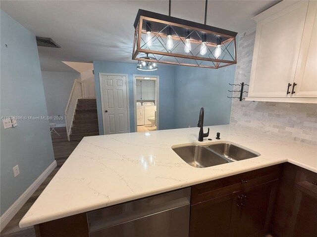 kitchen with decorative light fixtures, white cabinetry, separate washer and dryer, sink, and stainless steel dishwasher